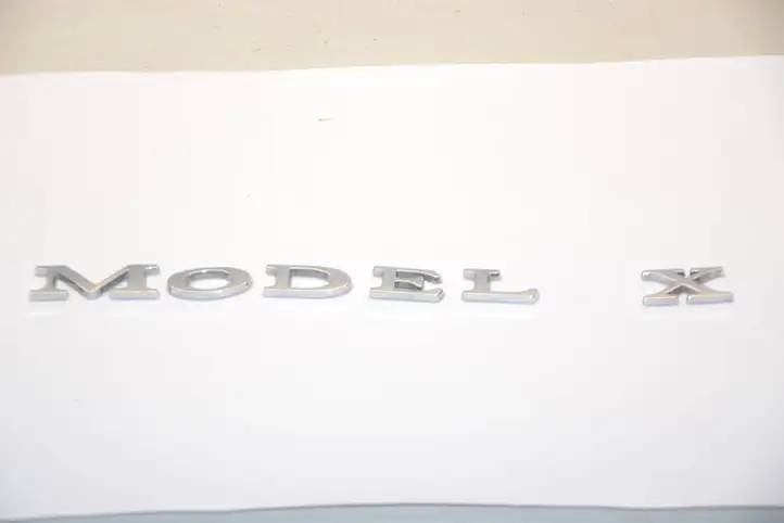 Tesla Model X (2015 - 2021) 104785500A Эмблема производителя — фото 1